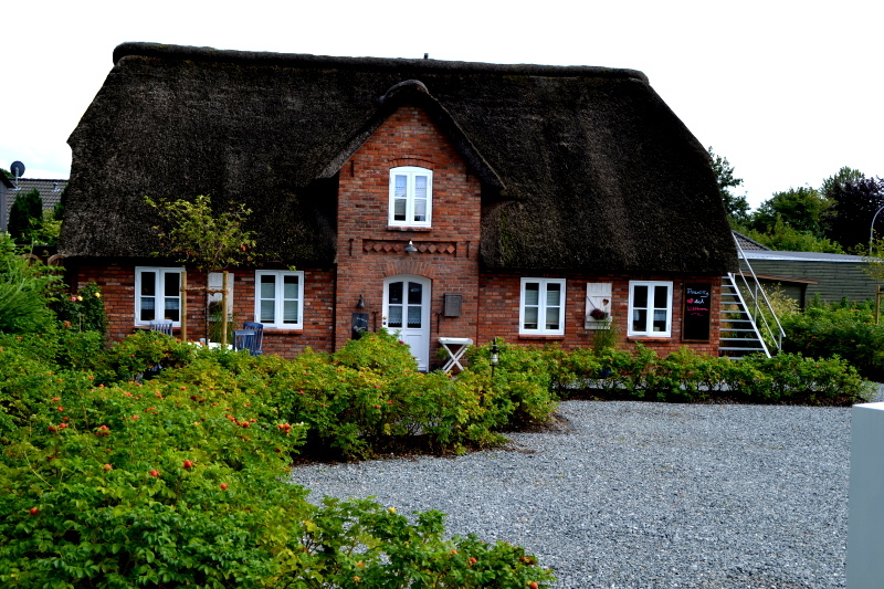 Einfamilienhaus mit grauem Dach und einem grünen gepflegtem Garen.